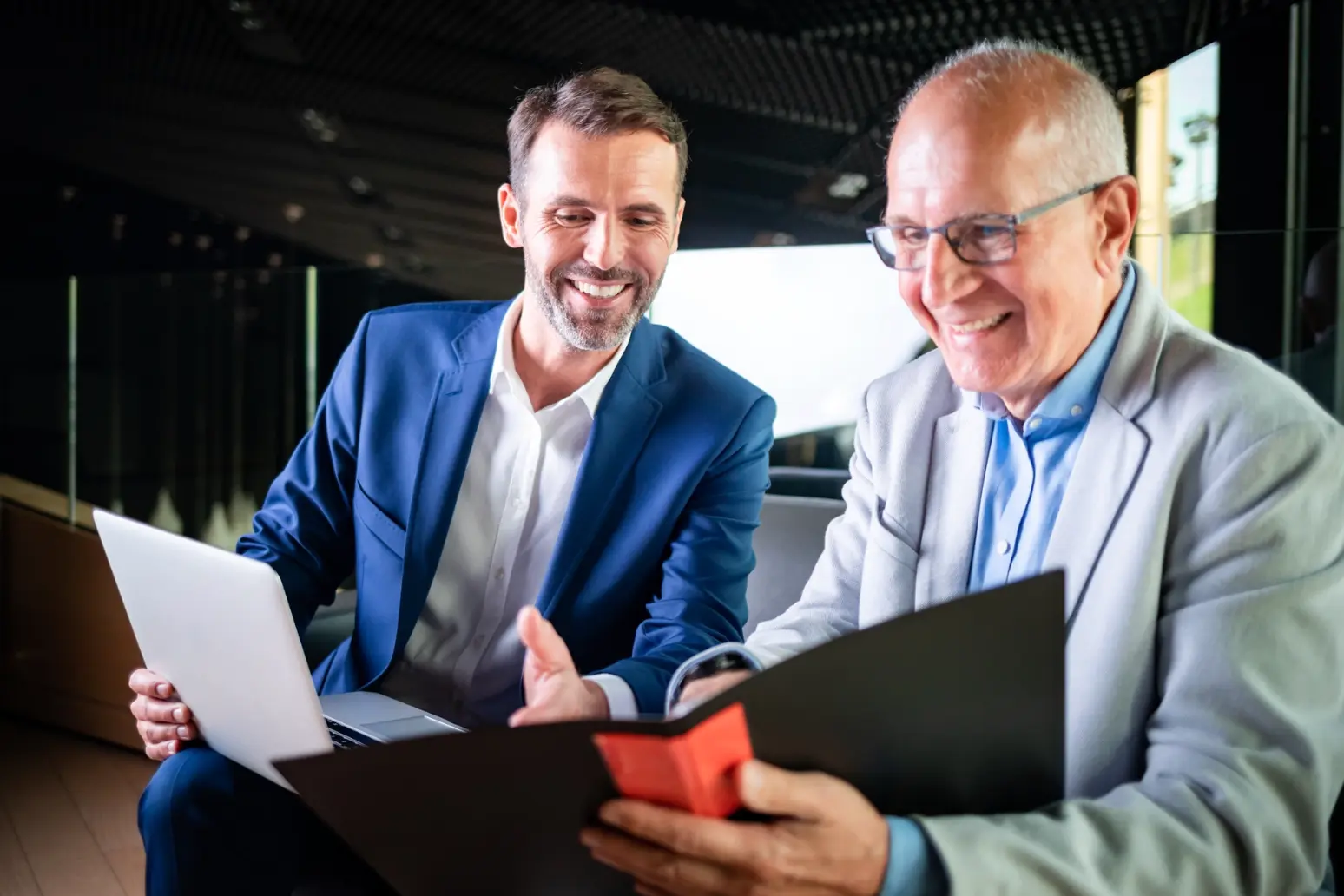 Two professionals smiling while reviewing documents