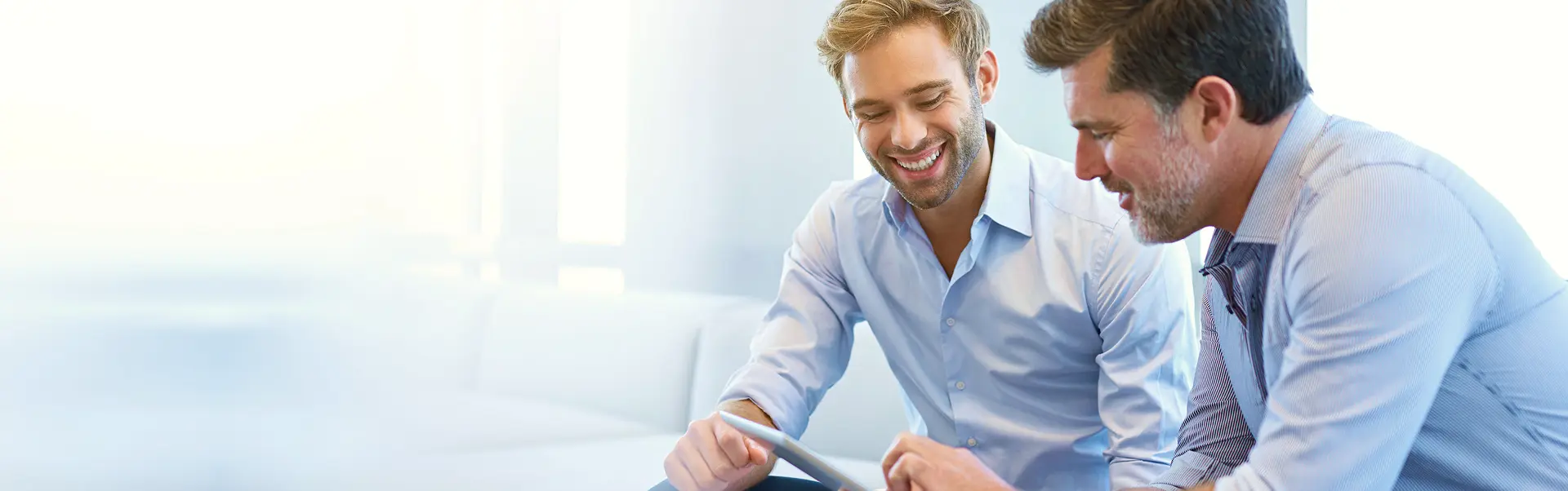 Two business professionals smiling while discussing something on a tablet